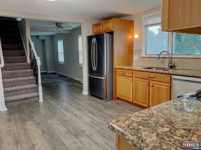 kitchen featuring ceiling fan, sink, light wood-type flooring, and stainless steel appliances