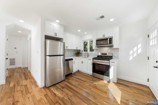 kitchen featuring white cabinets, appliances with stainless steel finishes, light wood-type flooring, and sink