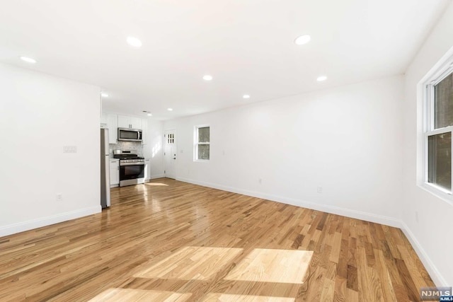 unfurnished living room with plenty of natural light and light hardwood / wood-style floors