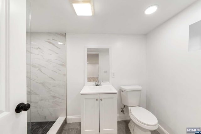 bathroom featuring tiled shower, vanity, and toilet