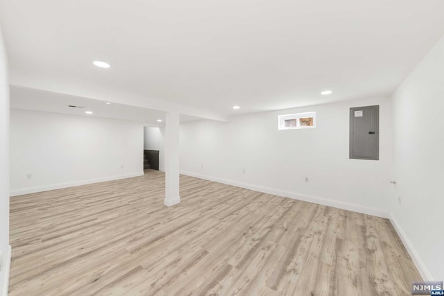 basement with light hardwood / wood-style floors and electric panel