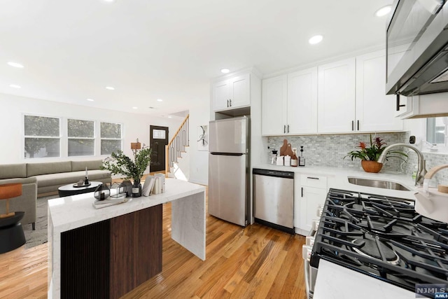 kitchen featuring white cabinets, sink, light hardwood / wood-style flooring, appliances with stainless steel finishes, and a kitchen island