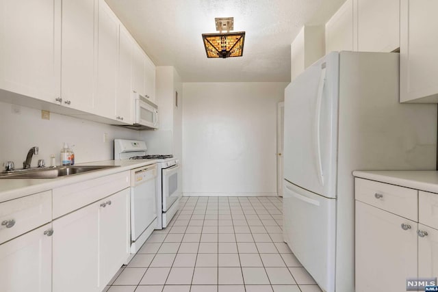 kitchen with white cabinets, white appliances, sink, and light tile patterned floors