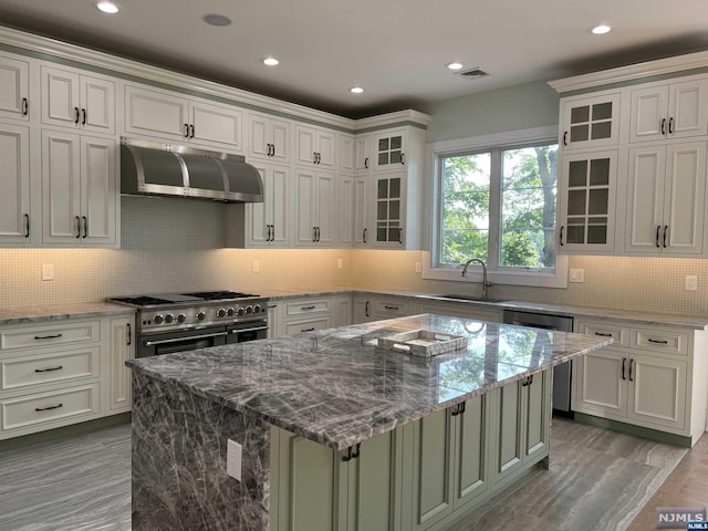 kitchen with ventilation hood, a kitchen island, light stone countertops, and hardwood / wood-style flooring