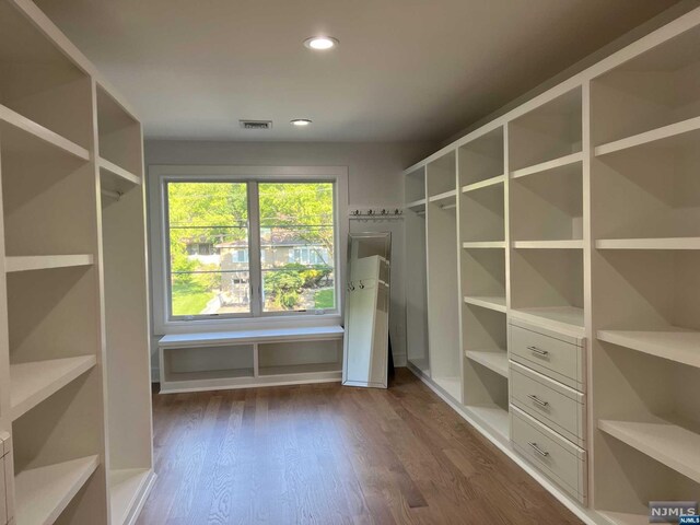 walk in closet with dark hardwood / wood-style floors