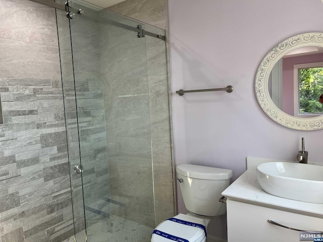 bathroom featuring vanity, toilet, and a shower with door