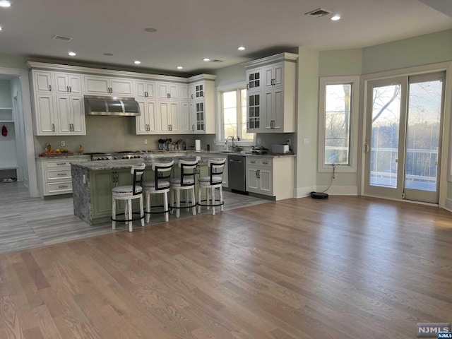 kitchen with a wealth of natural light, a breakfast bar, a center island, and range hood