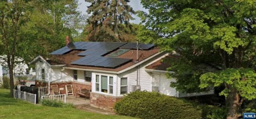 back of property featuring a lawn and solar panels