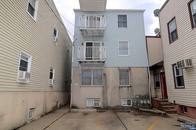 rear view of property featuring a wall mounted air conditioner and cooling unit