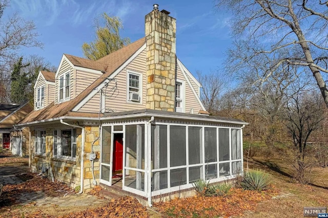 rear view of property featuring a sunroom and cooling unit