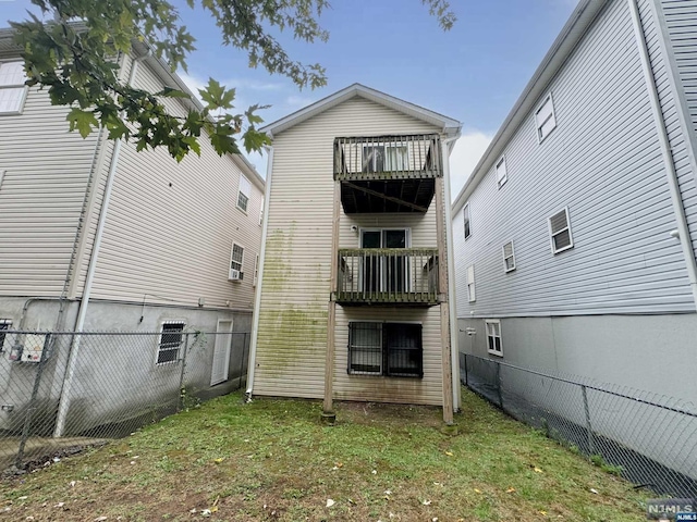 rear view of property with a lawn and a balcony