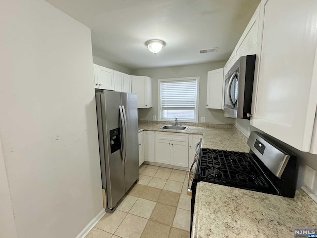 kitchen featuring white cabinets, stainless steel appliances, light tile patterned flooring, and sink