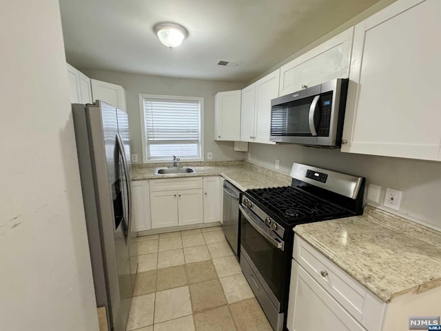 kitchen featuring white cabinets, sink, light stone countertops, light tile patterned floors, and stainless steel appliances