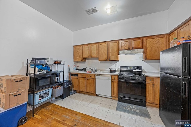 kitchen with sink, light hardwood / wood-style floors, and black appliances