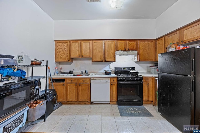 kitchen featuring black appliances, light tile patterned flooring, and sink