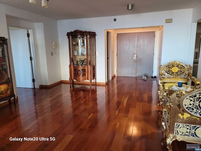 interior space featuring baseboards, a textured ceiling, and hardwood / wood-style floors