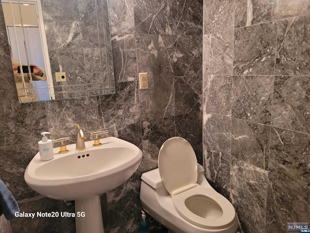 half bathroom with toilet, decorative backsplash, and tile walls