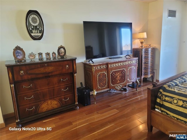 bedroom with dark wood-style floors, visible vents, and baseboards