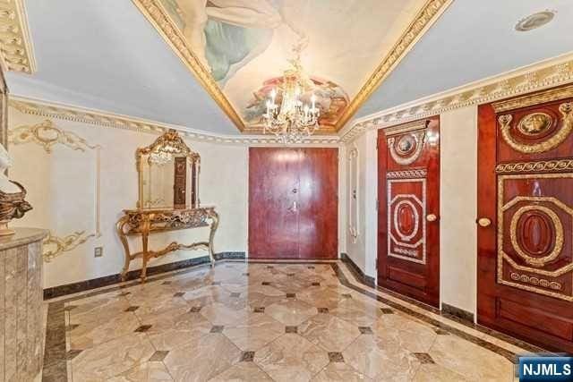 foyer entrance with lofted ceiling, baseboards, a chandelier, and crown molding