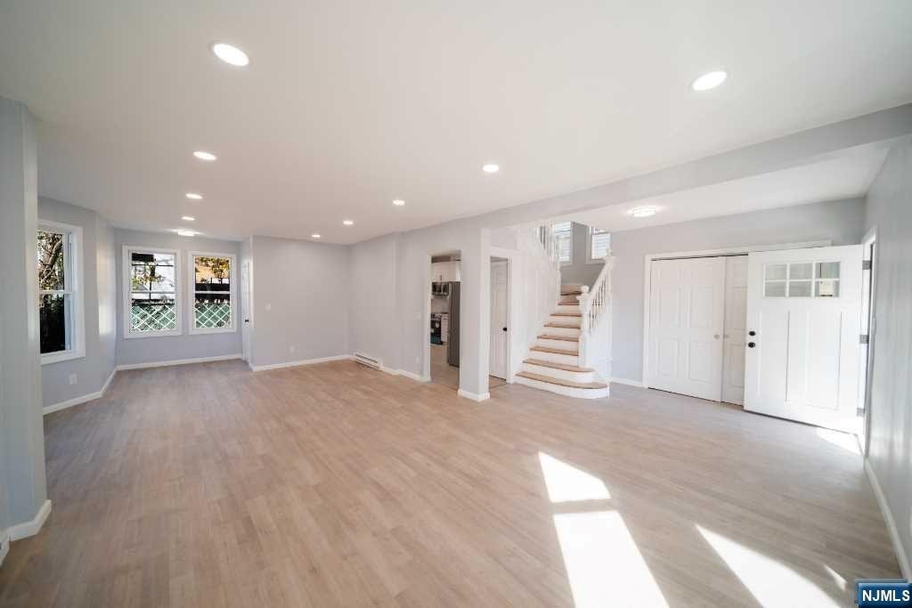 basement with stainless steel fridge and light wood-type flooring