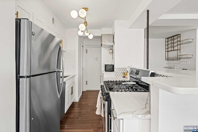 kitchen featuring white cabinets, stainless steel appliances, hanging light fixtures, and tasteful backsplash