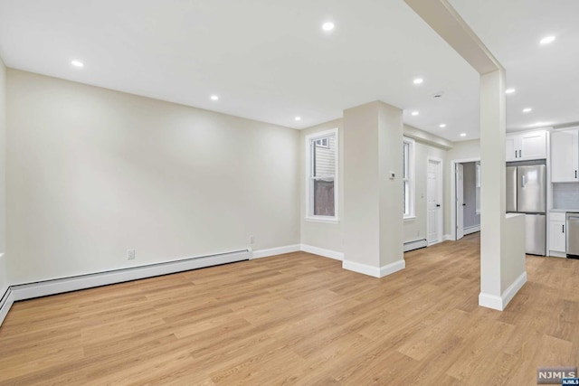 unfurnished living room featuring a baseboard heating unit and light wood-type flooring