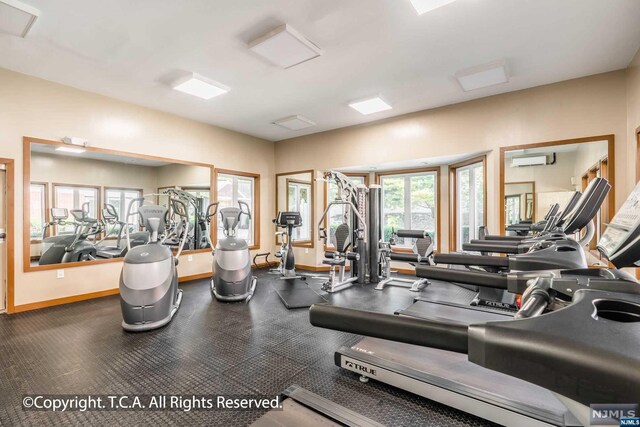 gym with a healthy amount of sunlight and a wall unit AC