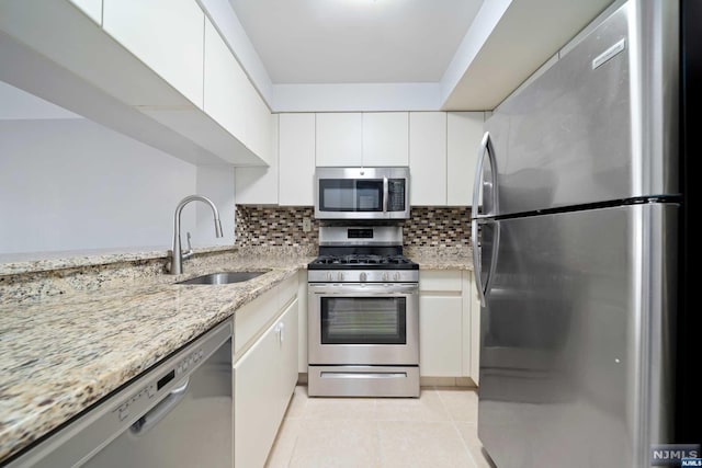 kitchen with sink, decorative backsplash, light stone counters, white cabinetry, and stainless steel appliances