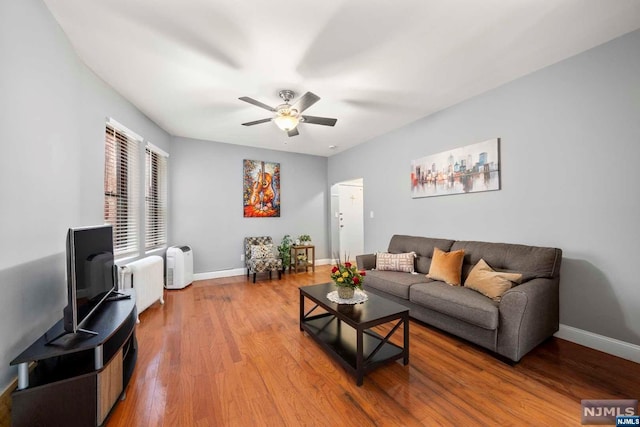 living room with radiator heating unit, ceiling fan, and wood-type flooring