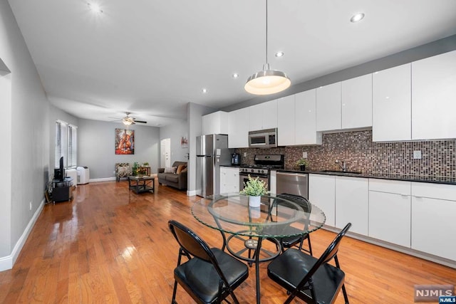 dining area featuring ceiling fan, light wood-type flooring, and sink