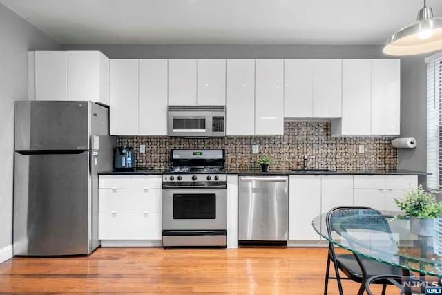 kitchen with white cabinetry, sink, tasteful backsplash, light hardwood / wood-style floors, and appliances with stainless steel finishes