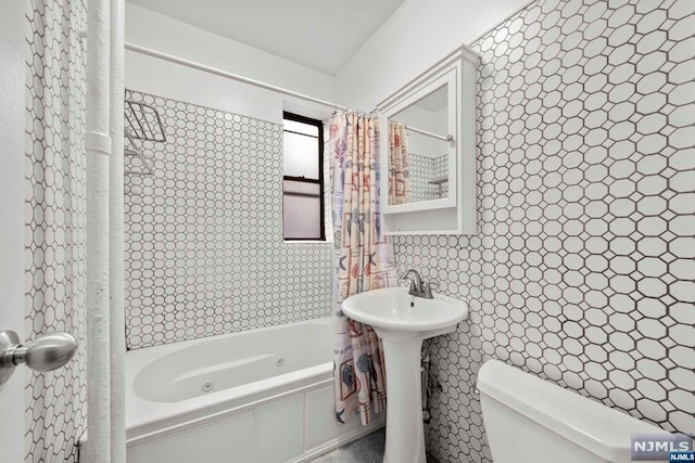 bathroom featuring toilet, shower / bathtub combination with curtain, and tile walls