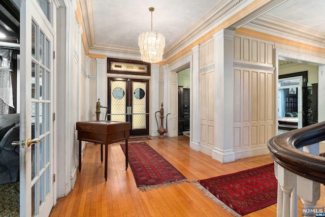 entrance foyer featuring french doors, an inviting chandelier, ornamental molding, and light hardwood / wood-style flooring