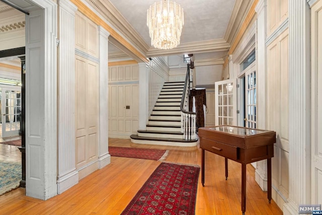 interior space featuring light wood-type flooring, crown molding, and an inviting chandelier