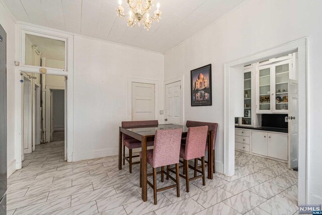 dining space with ornamental molding and a chandelier