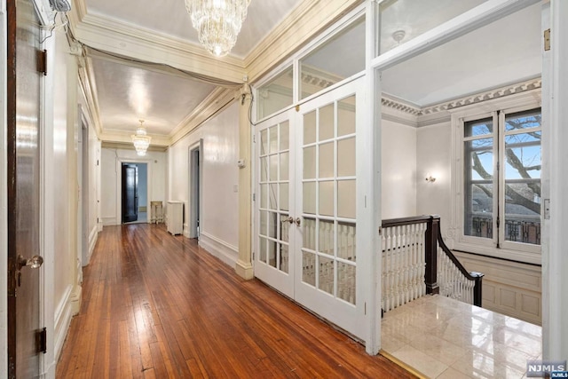 hall with french doors, crown molding, hardwood / wood-style flooring, a notable chandelier, and radiator heating unit