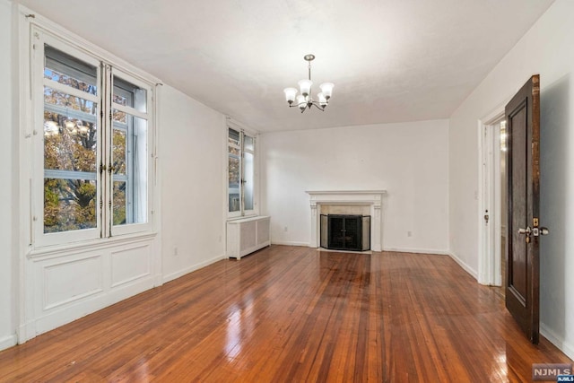 unfurnished living room with a notable chandelier, dark hardwood / wood-style floors, radiator heating unit, and a high end fireplace