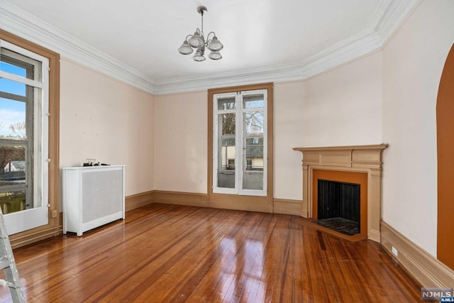 unfurnished living room with a chandelier, hardwood / wood-style floors, radiator heating unit, and ornamental molding