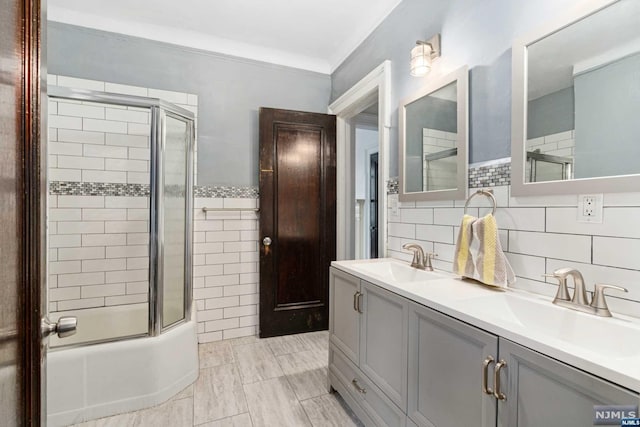 bathroom with combined bath / shower with glass door, vanity, crown molding, tile walls, and tile patterned flooring