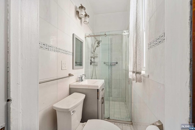 bathroom featuring tile walls, vanity, an enclosed shower, and toilet