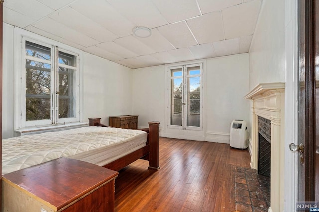 bedroom with a premium fireplace and dark hardwood / wood-style flooring