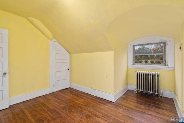 additional living space with radiator heating unit, dark hardwood / wood-style floors, and vaulted ceiling