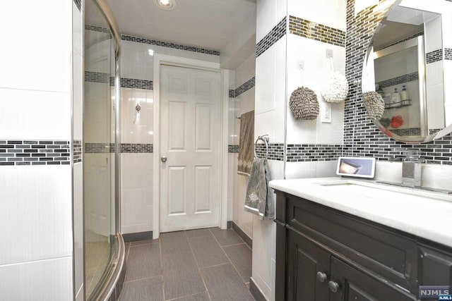 bathroom featuring vanity, a shower with door, and tile walls