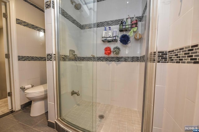 bathroom with a shower with shower door, tile walls, and toilet