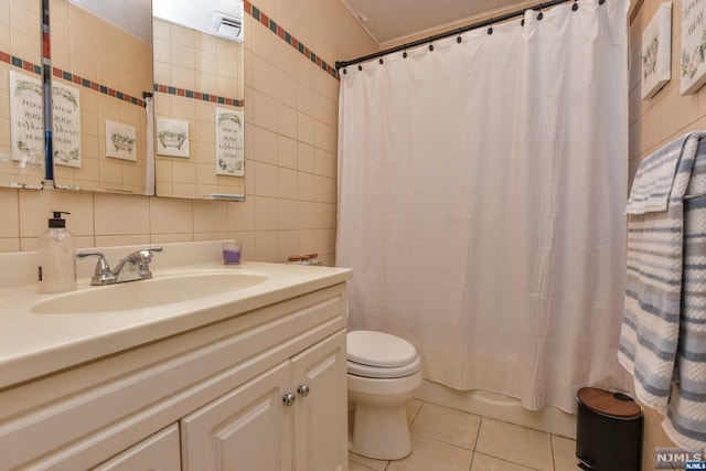 bathroom featuring tile patterned floors, toilet, tile walls, and tasteful backsplash