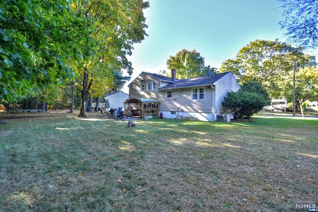 back of house with a gazebo, cooling unit, a trampoline, and a yard