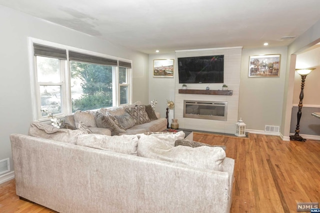 living room featuring a large fireplace and light hardwood / wood-style flooring