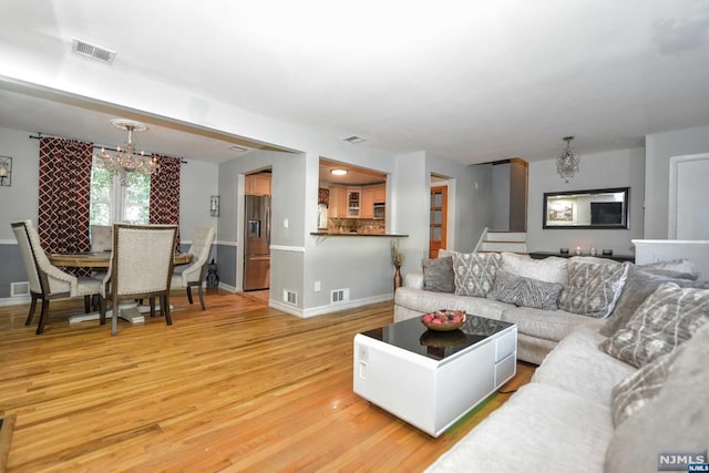 living room with light hardwood / wood-style floors and a notable chandelier