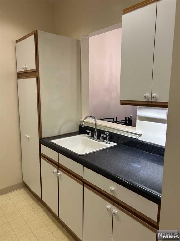 kitchen featuring white cabinets, light tile patterned floors, and sink