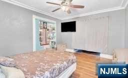 bedroom with ceiling fan, hardwood / wood-style flooring, and ornamental molding